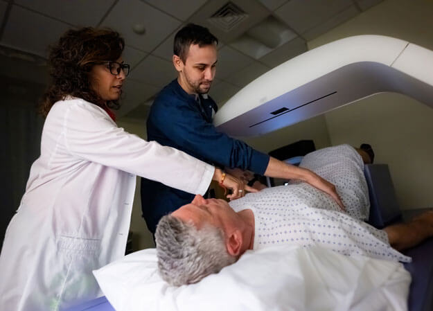 Medical imaging student and professor perform a diagnostic imaging procedure on a patient.