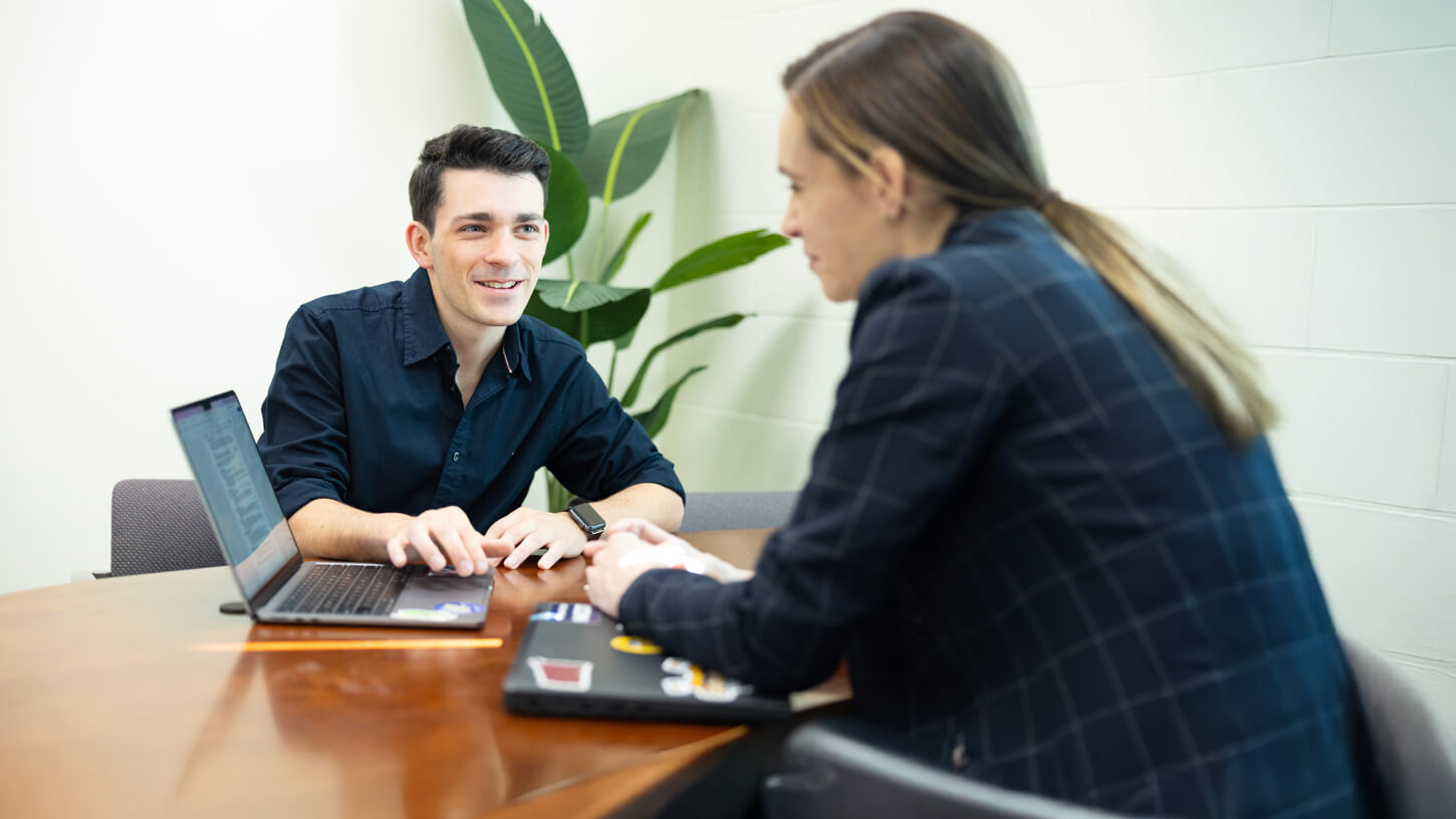 A student shows their laptop screen to a faculty member during a career consultation session.