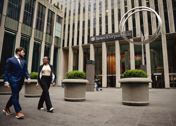 2 students walking in NYC out front of the New Corporation building