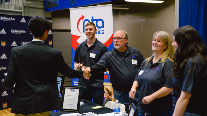 An engineering student shakes hands with a corporate affiliate.