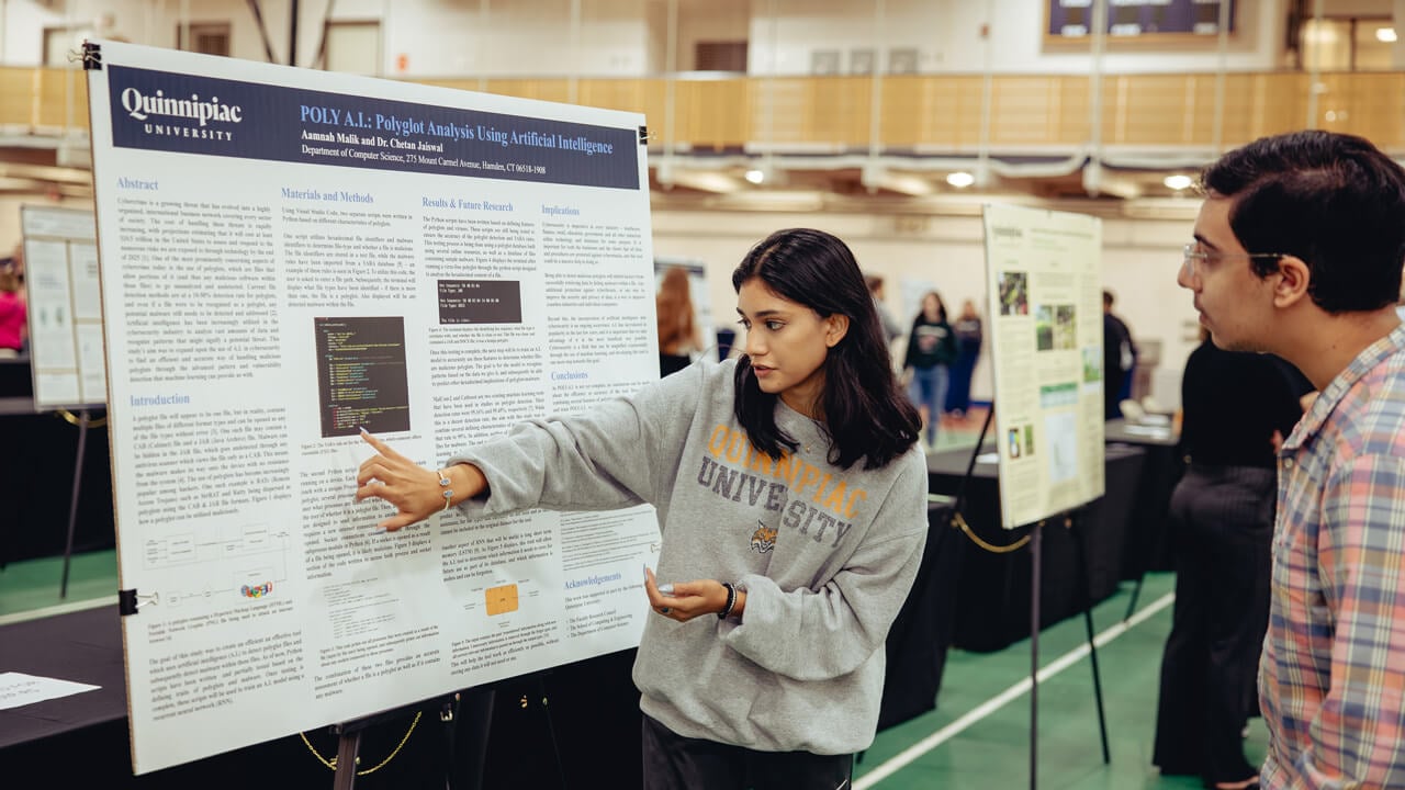 A student points to her academic poster as she presents her research to an Exploratorium attendee.